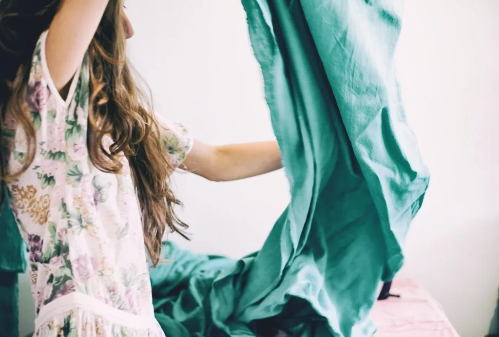 Young girl making her bed with teal sheets